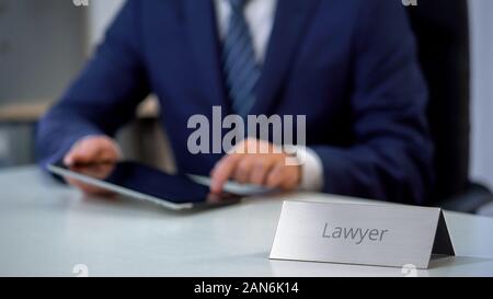 Serious lawyer working on tablet pc, preparing to important case, justice Stock Photo