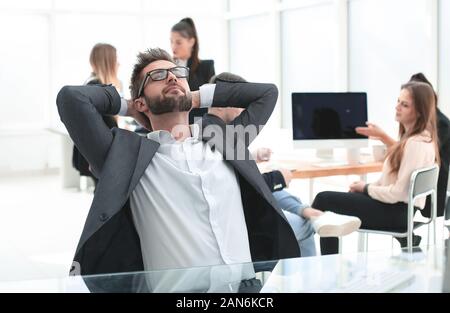 brooding young businessman sitting at an office Desk Stock Photo
