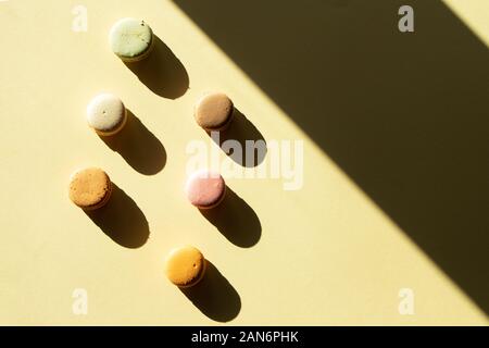 Contemporary flat lay composition pastel macaron on light yelow backgraund with dark shadow. Stock Photo
