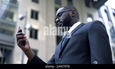 Business application, serious afro-american businessman working on smartphone Stock Photo