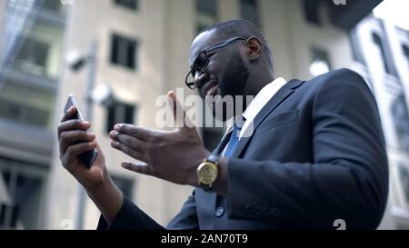 Businessman gets upset after read bad news on smartphone, fired, trouble at work Stock Photo