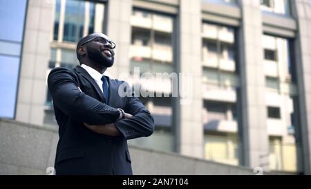 Afro-american man in suit looks up into bright future, motivated for success Stock Photo