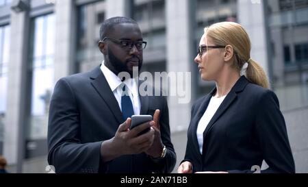 Office workers using smartphone, texting with business partner, checking e-mail Stock Photo