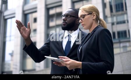 Engineers compare project on tablet with construction site, high-rise building Stock Photo
