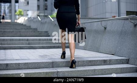 Businesswoman coming upstairs to office center, going to work, busy lifestyle Stock Photo