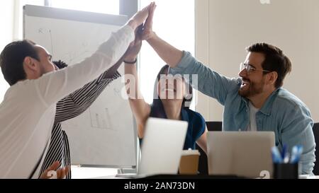 Overjoyed diverse employees give high five at office meeting Stock Photo