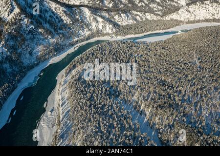 Picturesque landscape in the Altai mountains with snow-capped peaks under a blue sky with clouds in winter with green river Katun. White snow and calm Stock Photo