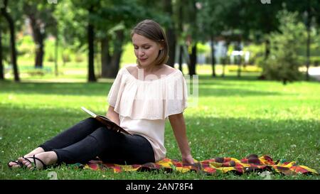 Lonely lady reading book in park, tips for women how to find caring husband Stock Photo