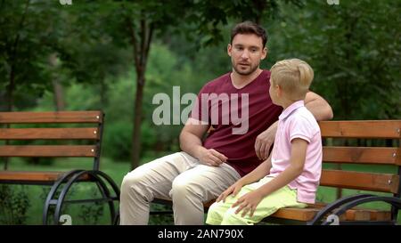 Conversation between father and son in park, loving dad giving advices to kid Stock Photo