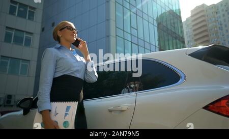 Positive woman talking on phone, beginning of work day, successful business lady Stock Photo
