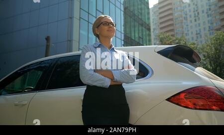 Self-confident business lady crossing hands looking into bright future, success Stock Photo