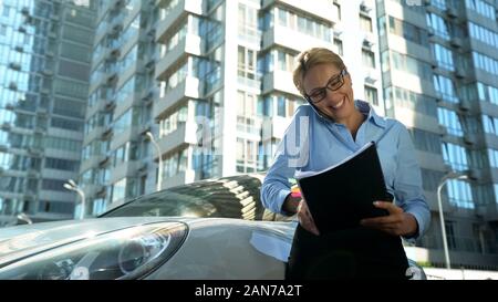 Woman in business suit speaking by phone, happy about successful contract Stock Photo