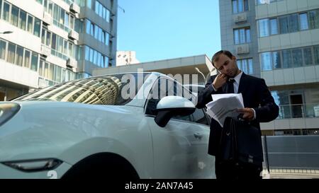Busy man reading papers in his hand talking on phone, business issues of company Stock Photo