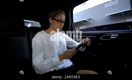 Woman annoyed by bad service and glitches, going to throw fake phone out of car Stock Photo