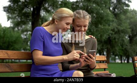 Mother and daughter surfing net on smartphone and laughing, social networking Stock Photo