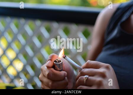 Woman holding cigarette and lighter in hand  Stock Photo