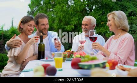 Old and middle-aged couples toasting, holding wine glasses, happy marriage Stock Photo