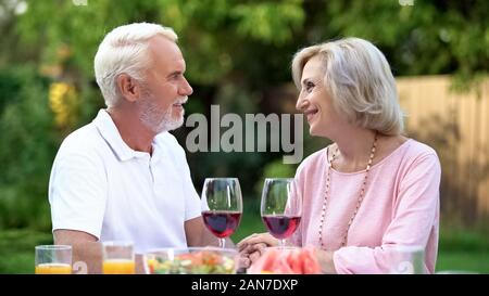 Old couple celebrating anniversary, drinking wine, everlasting love relations Stock Photo