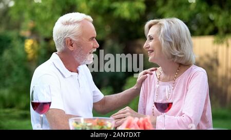 Cheerful senior couple having romantic date in backyard, meeting website Stock Photo