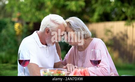Seniors sitting at table and remembering their life together, happy marriage Stock Photo