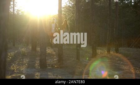 Pair of lovers spending active weekend together in wood, magic hour, happiness Stock Photo