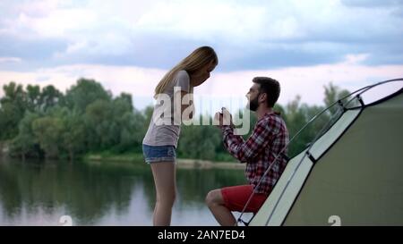 Man making proposal to beloved woman in beautiful forest during camping trip Stock Photo