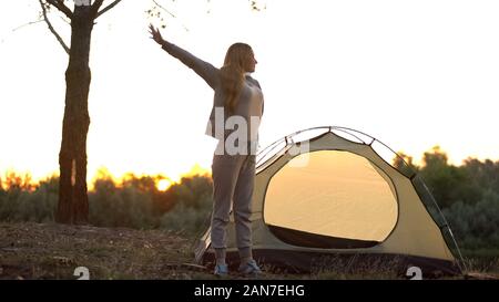 Lady stretching in morning, getting out of dome tent, ready for new adventure Stock Photo