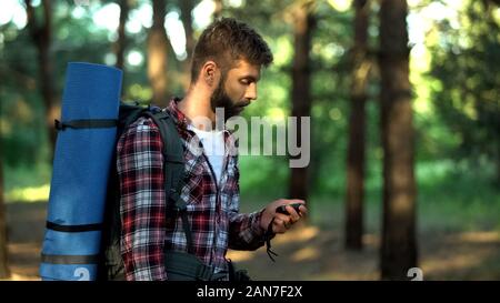 Male lost in forest using compass to navigate, finding way out from woods Stock Photo