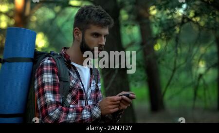 Man orienteering in forest, using navigational compass, survival classes Stock Photo