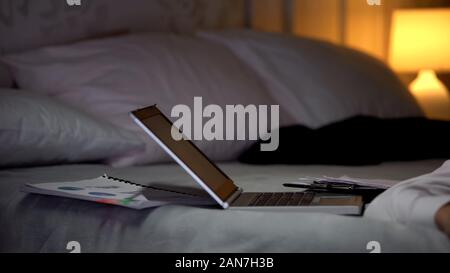 Busy lifestyle concept, laptop and documents lying on bed, businessman sleeping Stock Photo