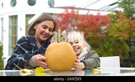 Kid and teacher preparing pumpkin for school party, additional handicraft class Stock Photo