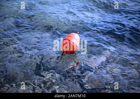 Orange buoy floating in calm blue water. Stock Image. Stock Photo