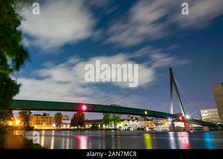 A small cable stayed bridge over a river for pedestrians at night, stars, clouds, long exposure, colorful, Kaisersteg in Berlin Schoeneweide Stock Photo