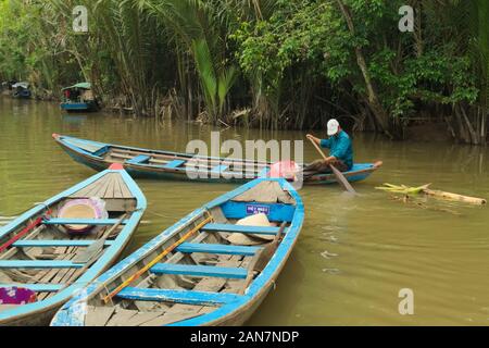 Vietnamese man rowing on a boat along one of the tributaries of Mekong River near My Tho, Vietnam. Stock Photo