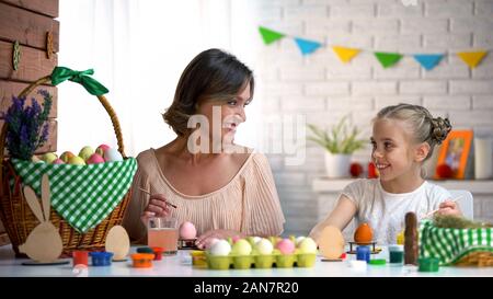 Woman teaching girl to paint eggs for Easter holiday, art lesson, handmade Stock Photo