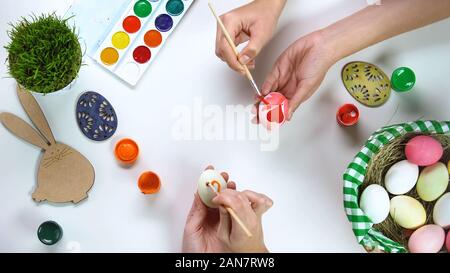 Women hands decorating eggs on table, Easter traditions, family connection Stock Photo