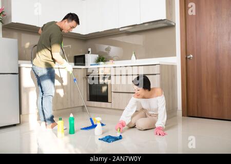 Young happy Asian couple is having fun while doing cleaning at home. Stock Photo