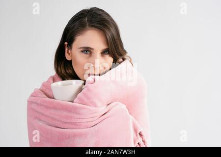 Woman wrapped in blanket holding a mug of hot tea Stock Photo
