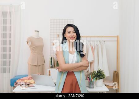 Portrait of happy Asian fashion designer businesswoman at studio. Smiling, standing, looking at camera. Stock Photo