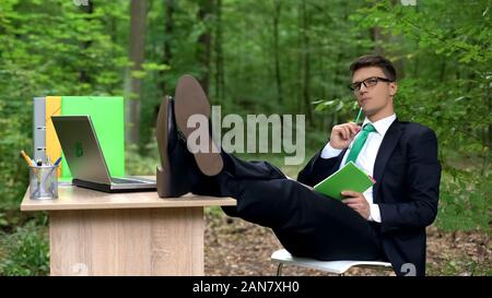 Thoughtful businessman making list of creative ideas, inspired by nature in park Stock Photo