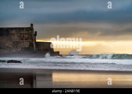 Detail of the Sao Juliao da Barra Fort with its reflection on the beach sand and the waves brealing at Carcavelos, Oeiras, Portugal Stock Photo