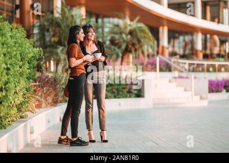 Two pretty women standing and talking with their drinks. Stock Photo
