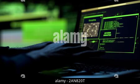 Close-up hacker hands working on laptop, selecting password, access granted Stock Photo