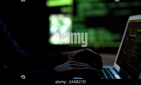 Programmer writing code for malware, remote hacking of bank accounts, cybercrime Stock Photo