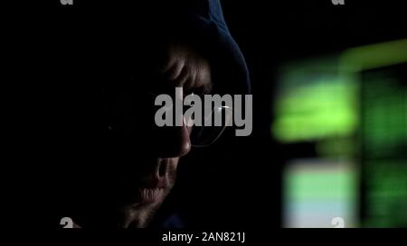 Hacker in glasses attentively reading information leaked from deep internet Stock Photo