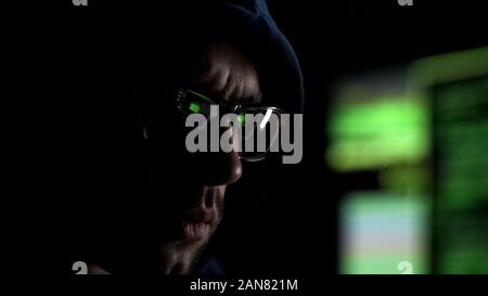 Man in hoodie wearing glasses with app synchronized with computer, digital eye Stock Photo