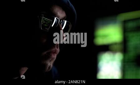 Programmer intently looking at monitor checking data, reflection in glasses Stock Photo