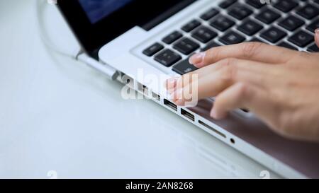 Female hand typing on laptop keyboard, personal computer use at office or home Stock Photo