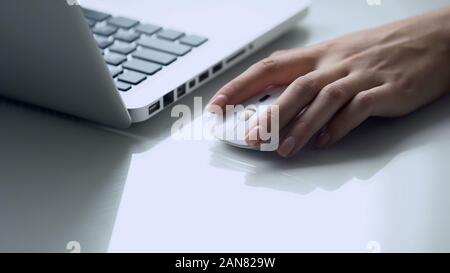 Left-handed female using wireless mouse with laptop, modern personal computer Stock Photo