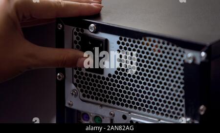 Hand switching off desktop pc button on power supply, modern computer technology Stock Photo